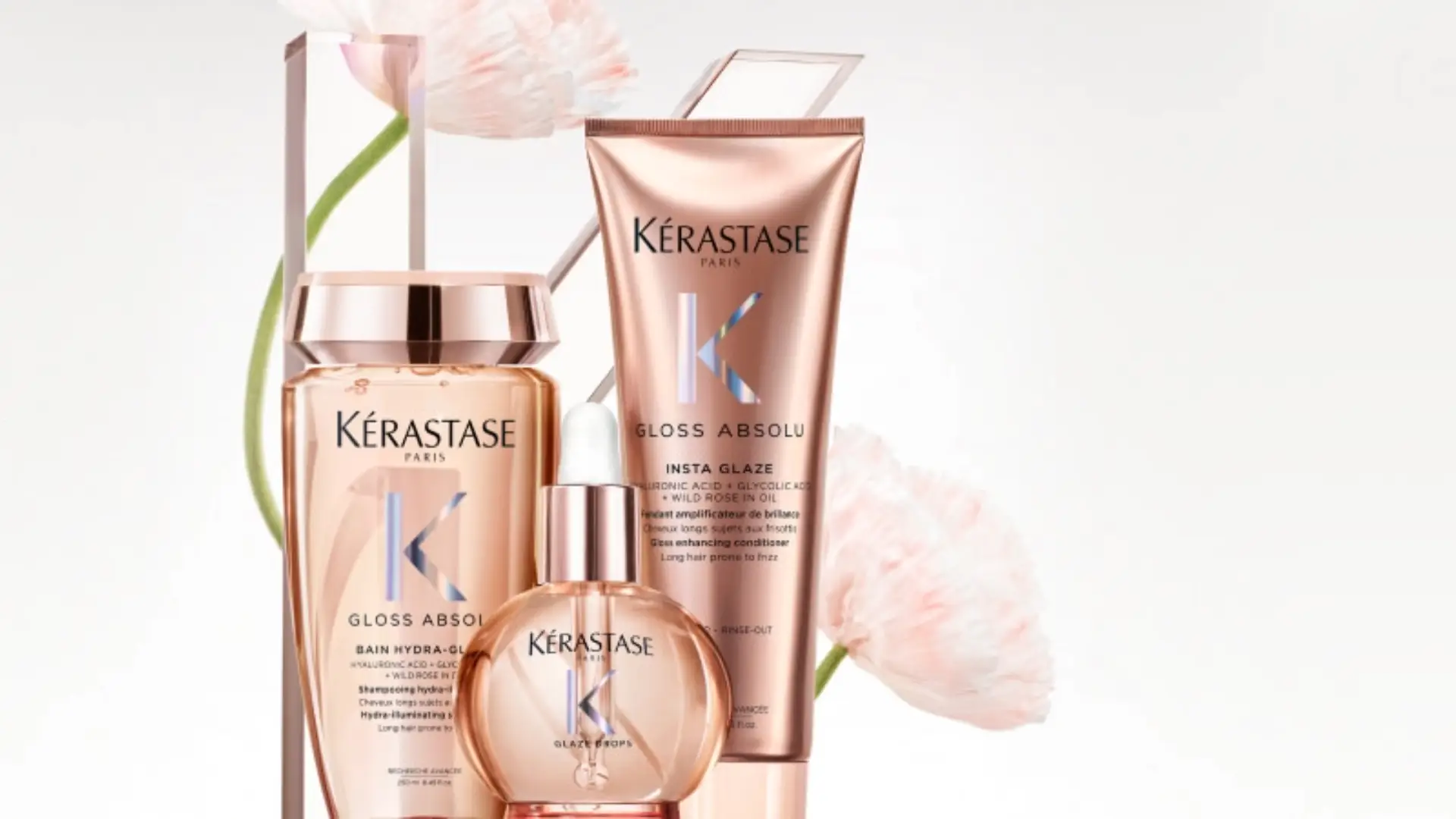 Produtos da linha Kérastase Gloss Absolu – shampoo, condicionador, spray e óleo – dispostos sobre superfície elegante, em destaque com iluminação suave.
